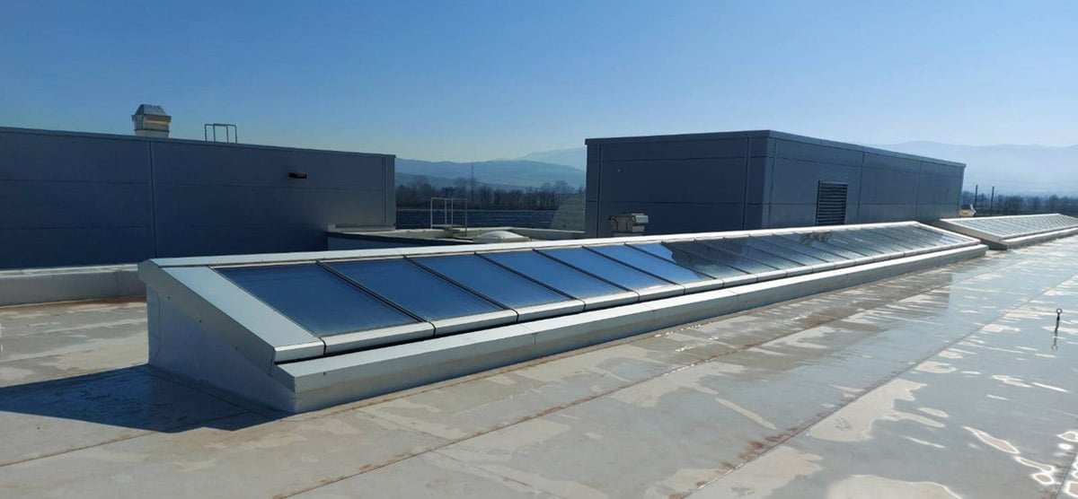 Pultdach-Lichtband mit sieben Glasmodulen auf dem Dach eines Industriegebäudes.