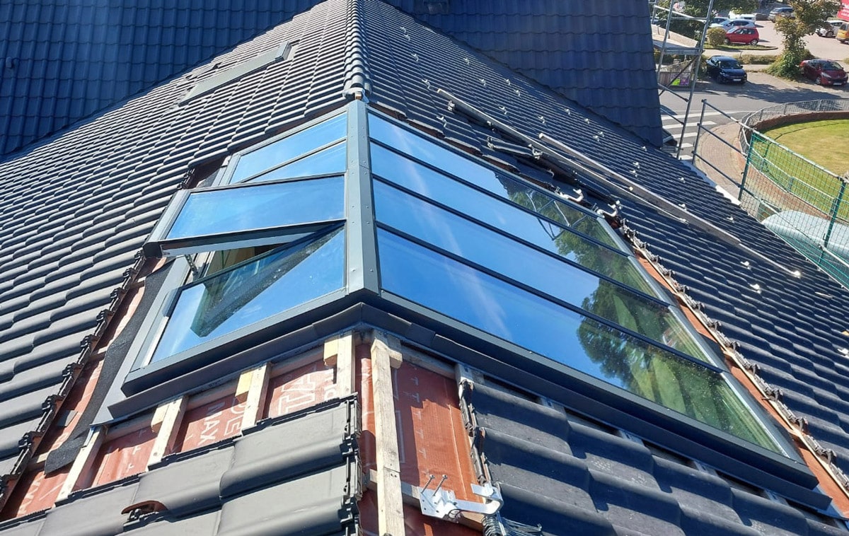Asymmetrische Firstverglasung Foto aus Dachhöhe: Asymmetrische Firstverglasung: die sonnenzugewandte Seite hat nur halb so hohe Fenstermodule.